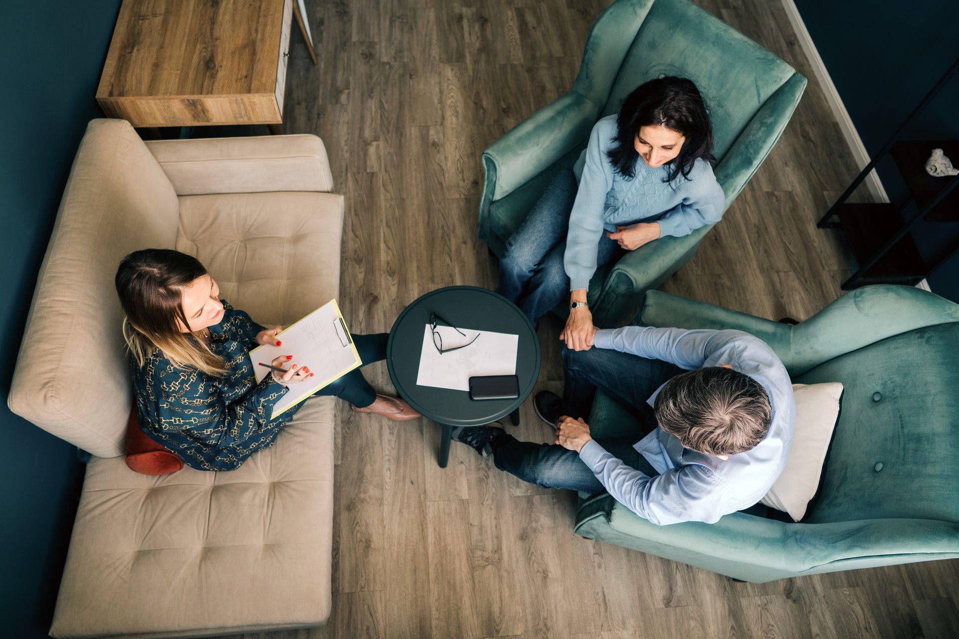 A group of people are sitting around a table in a living room.