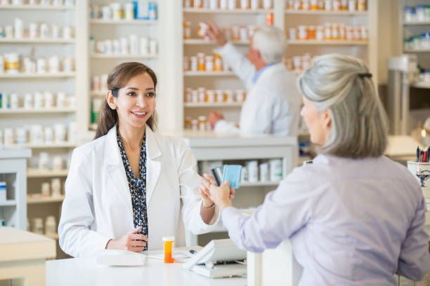 A female pharmacist is talking to an older woman in a pharmacy.