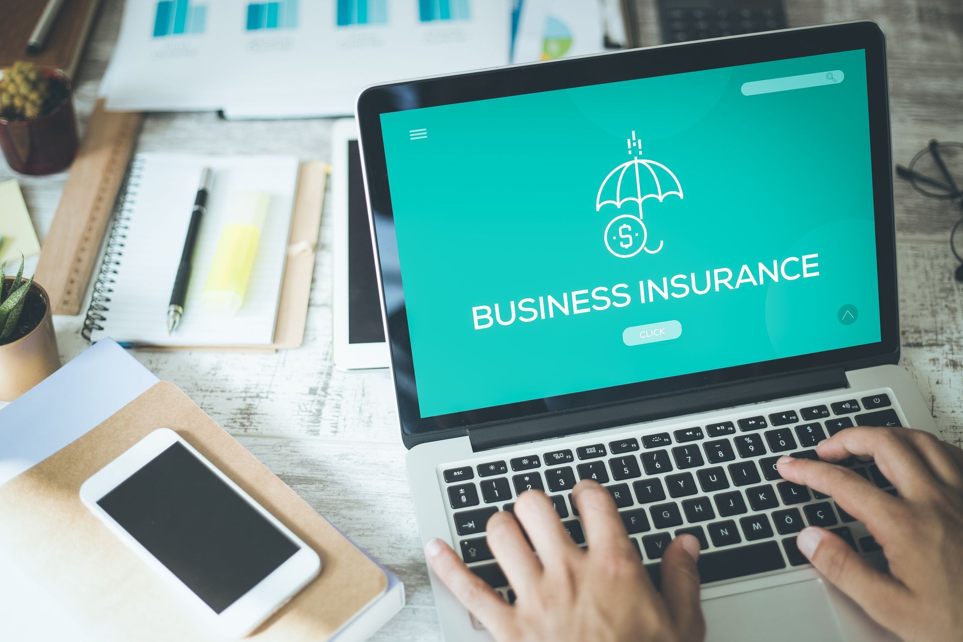 A person is typing on a laptop computer with the word business insurance on the screen.