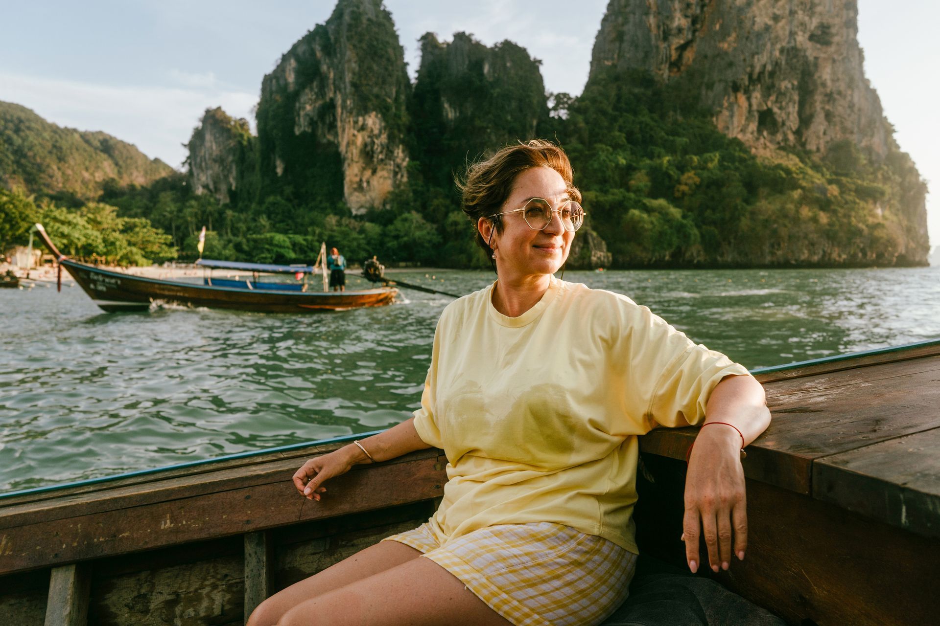 A woman is sitting on the side of a boat in the water.