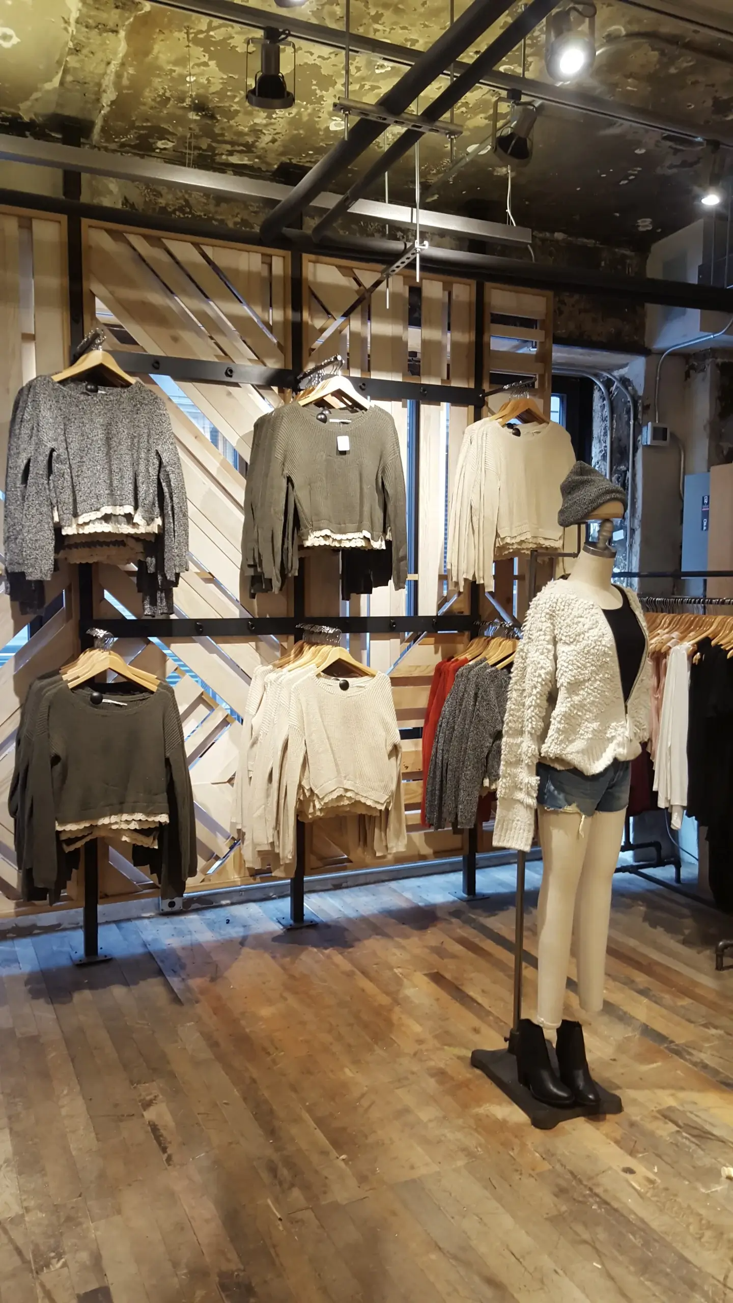 A mannequin is standing in front of a display of clothes in a store.