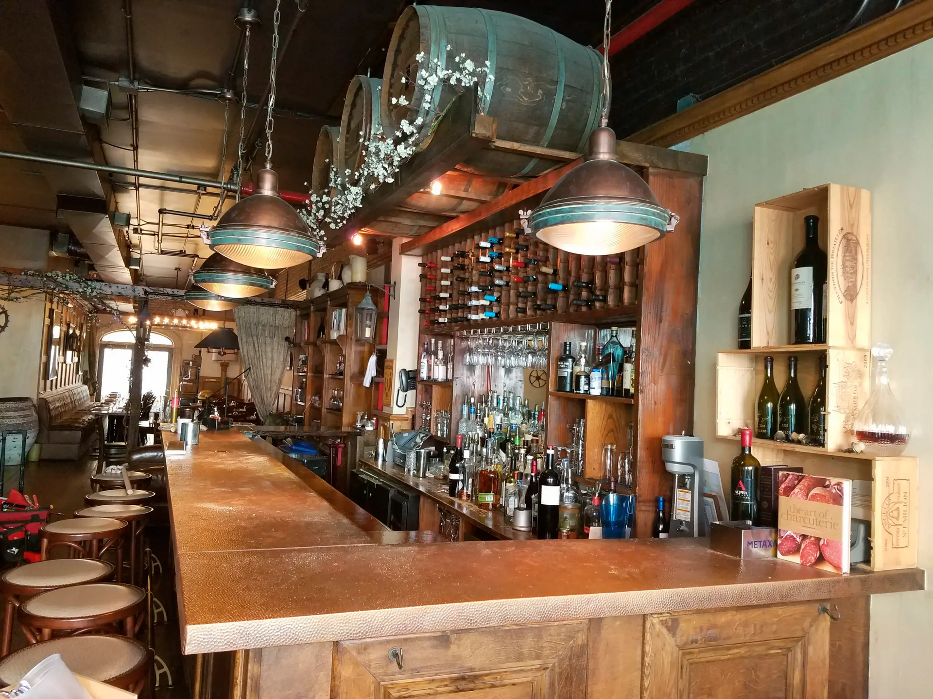 A long wooden bar in a restaurant with lots of bottles on shelves