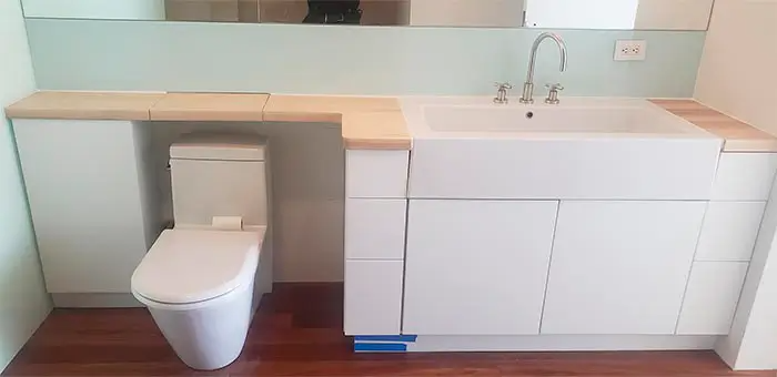 A bathroom with a toilet , sink and mirror.