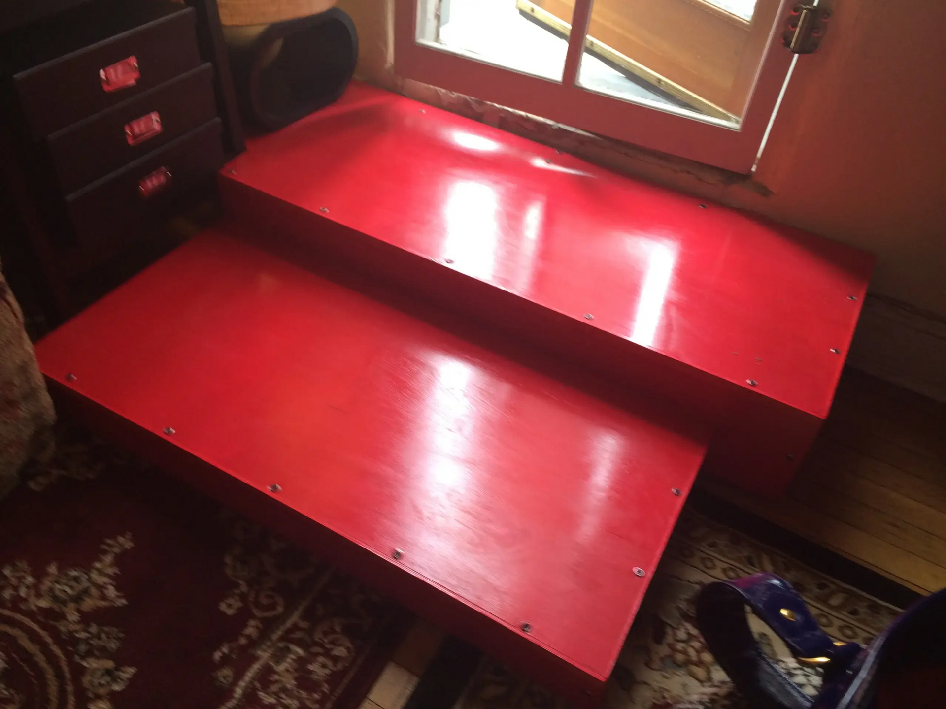 A red staircase in a room next to a window