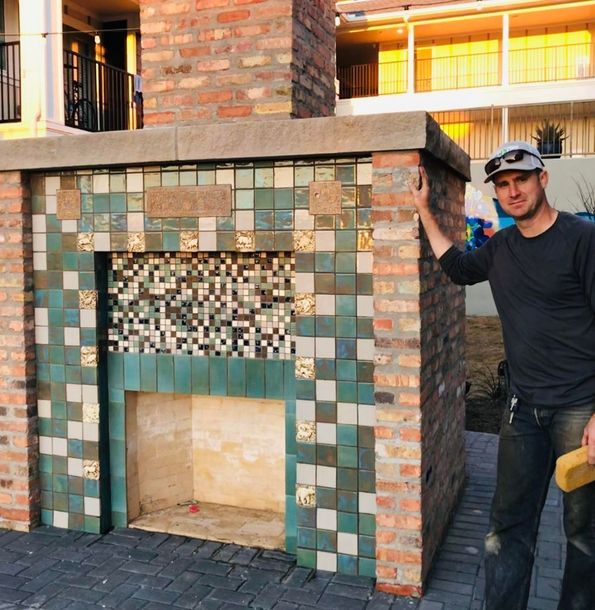 A man is standing in front of a brick fireplace