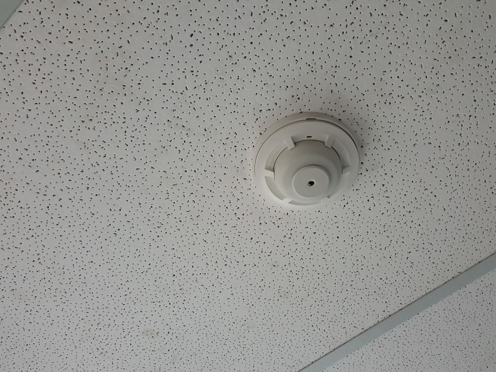 A White Smoke Detector Is Mounted To A White Ceiling — Davey Service & Maintenance Qld In Clinton, QLD