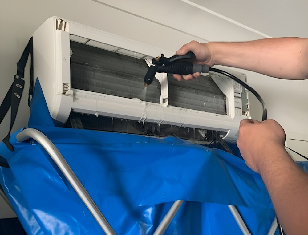 A Person Is Cleaning An Air Conditioner With A Spray Bottle — Davey Service & Maintenance Qld In Clinton, QLD
