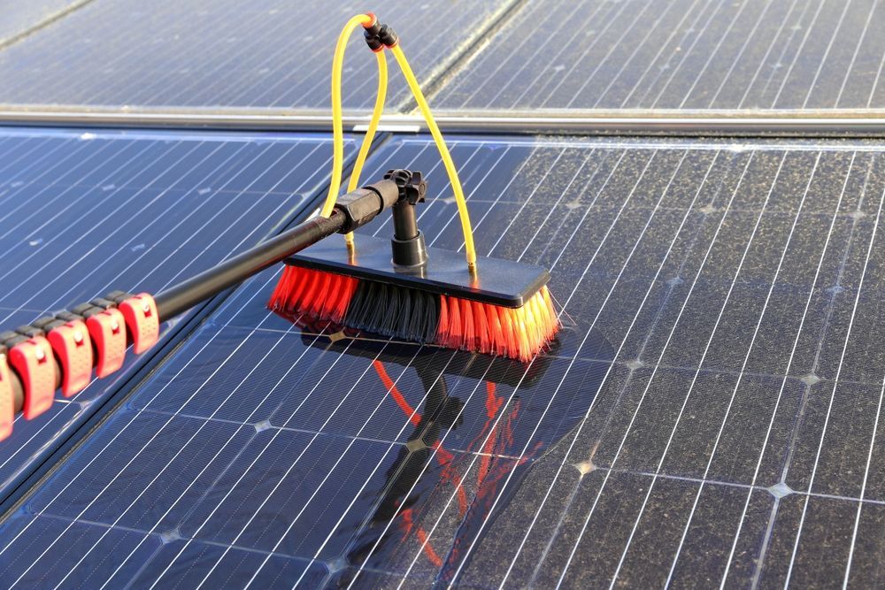 A Person Is Cleaning A Solar Panel With A Brush — Davey Service & Maintenance Qld In Clinton, QLD