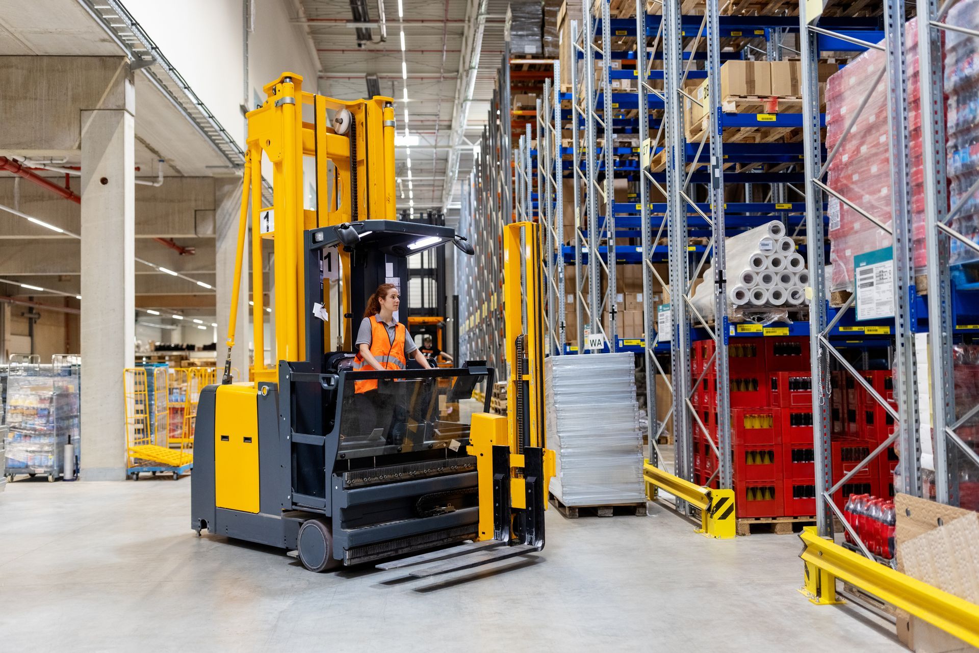 Woman operating a forklift in a warehouse, surrounded by shelves of goods. Woman operating a forklift in a warehouse, surrounded by shelves of goods.