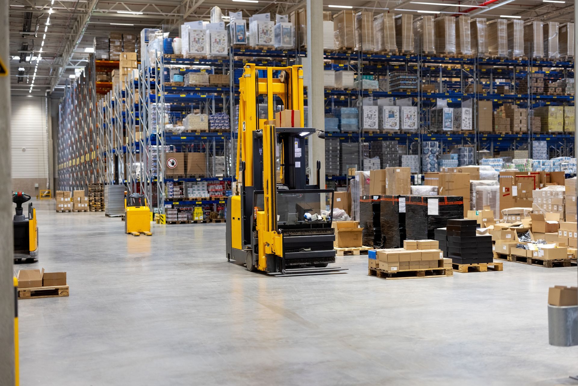 Yellow forklift in a warehouse, loading boxes onto tall shelves. Yellow forklift in a warehouse, loading boxes onto tall shelves.
