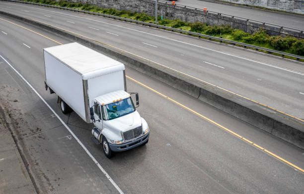 White box truck driving on multi-lane highway; daytime.