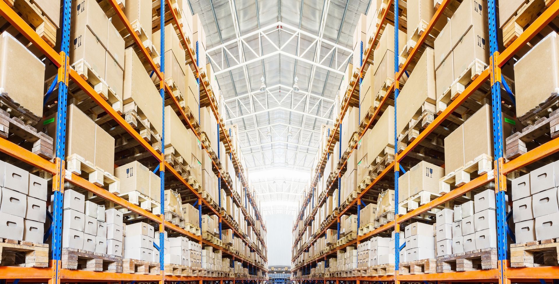 Warehouse interior with rows of shelves stacked with cardboard boxes.