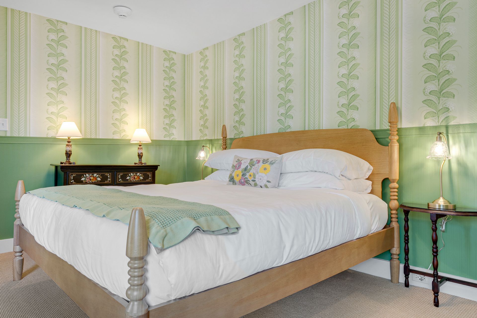 Bedroom with light green wallpaper, a wooden bed, and two nightstands.
