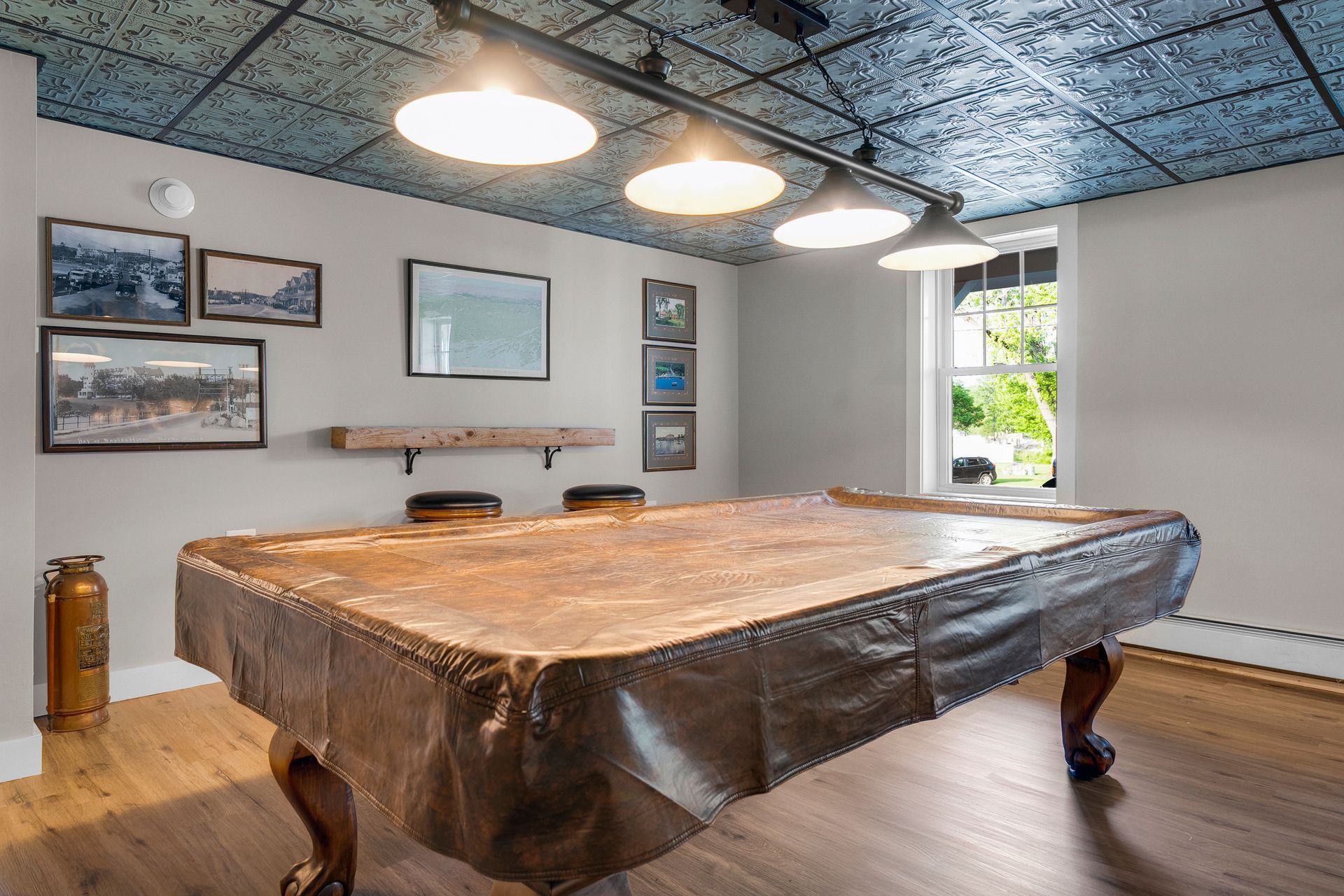 Pool table in a room with a decorative tin ceiling, track lighting, and historical photos.