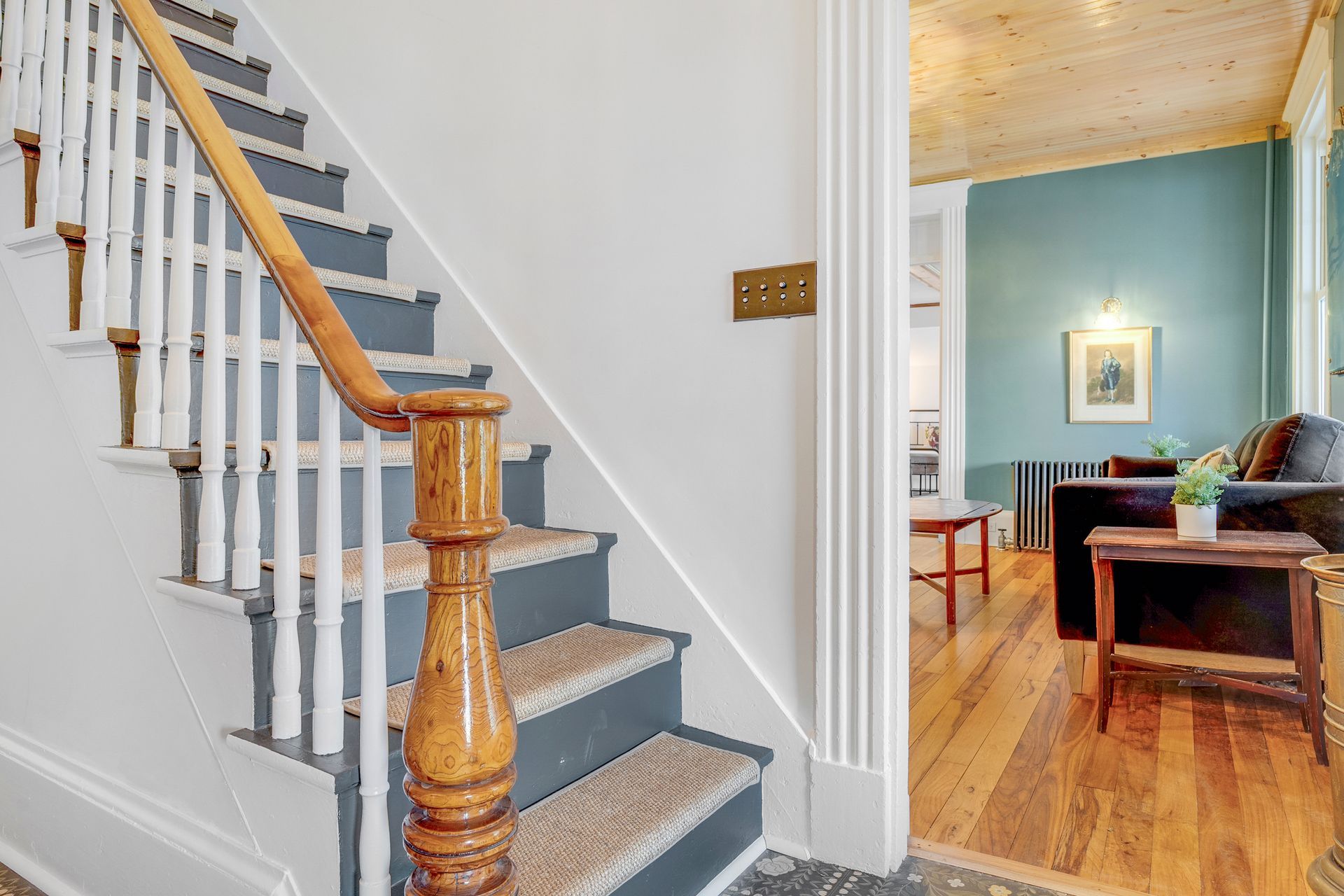 Staircase with wooden handrail, leading up to a teal-colored room.