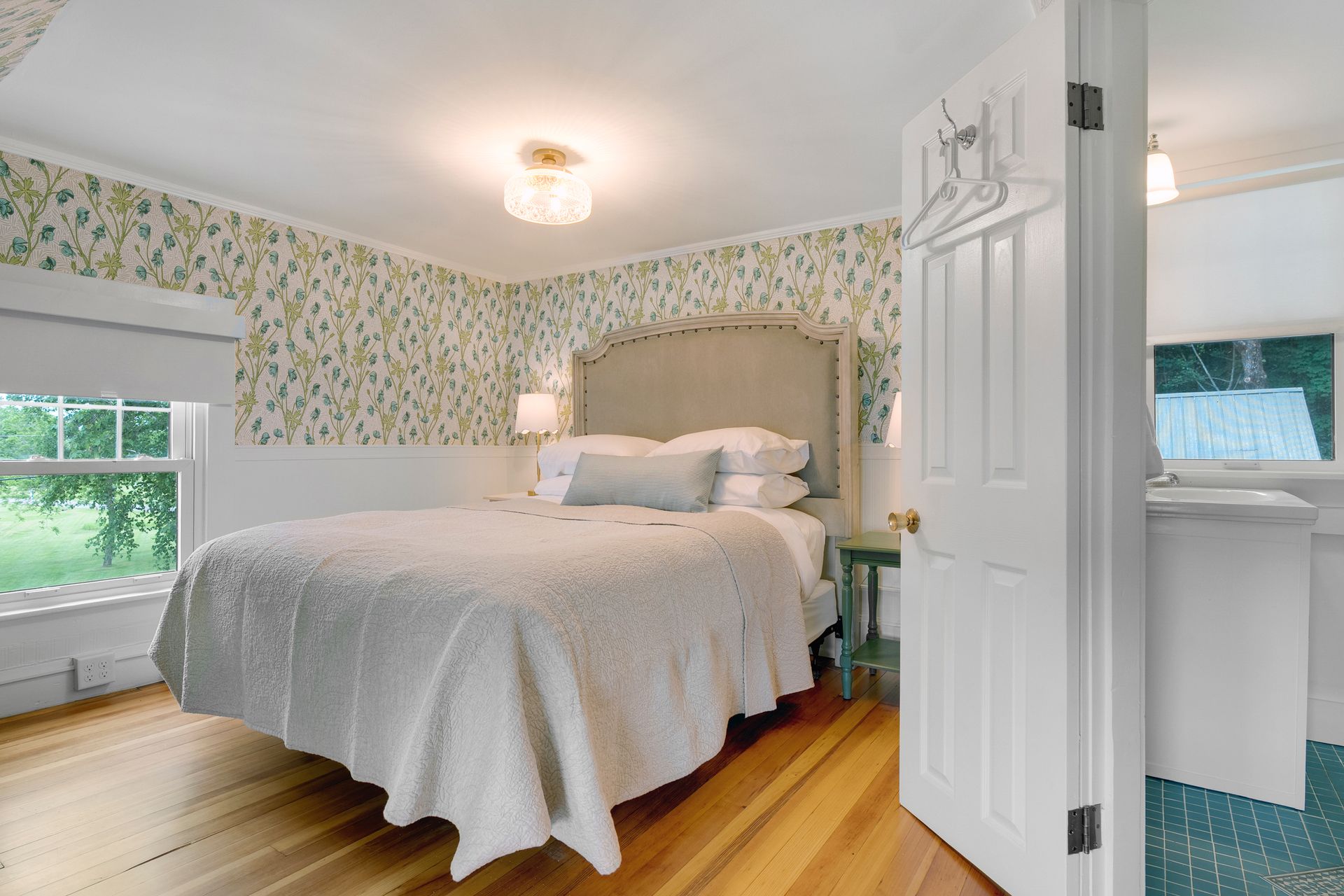 Bedroom with a bed, wallpaper, window, and a door leading to a bathroom.