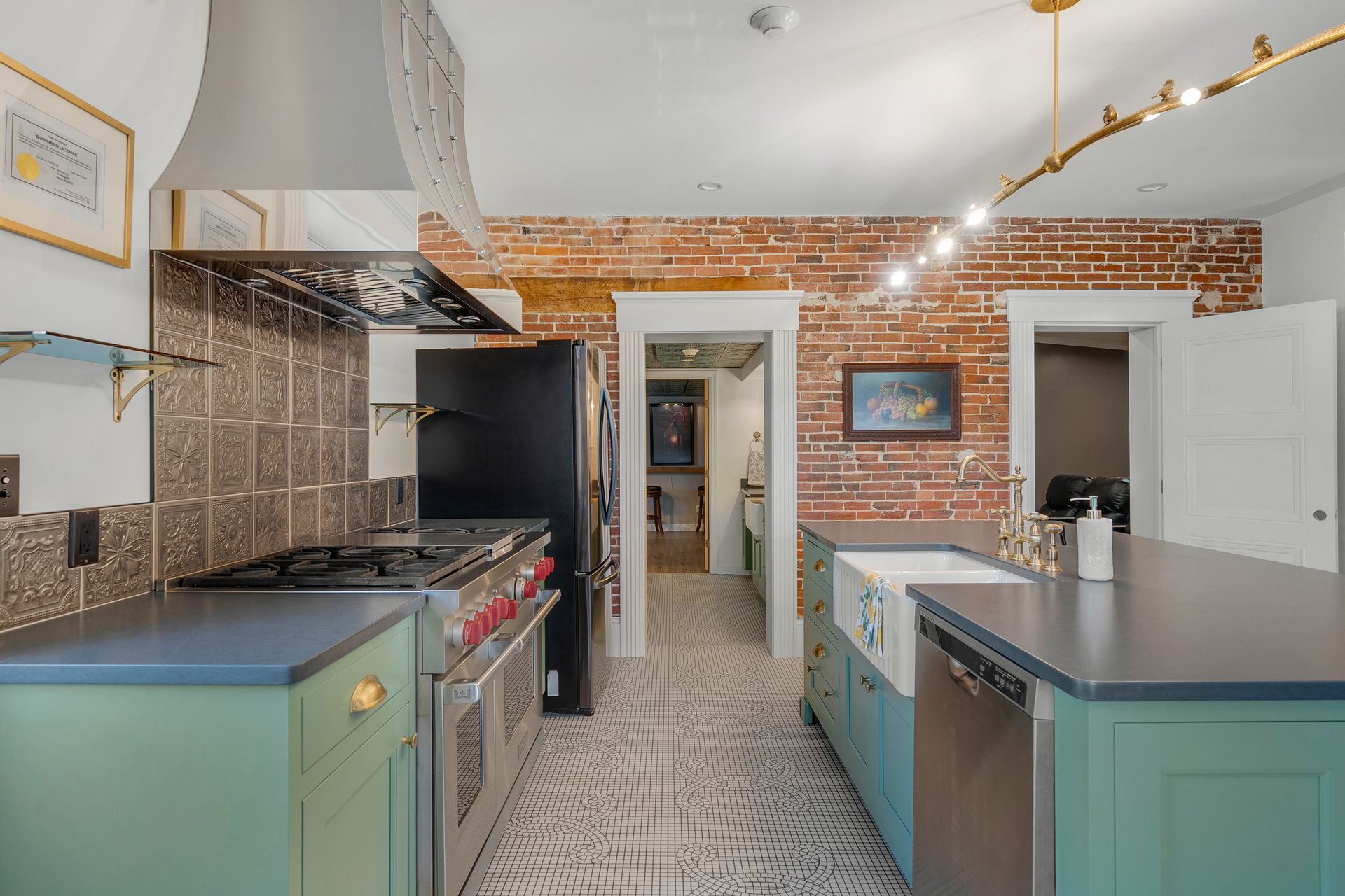 A kitchen with exposed brick, green cabinets, and a black stove.