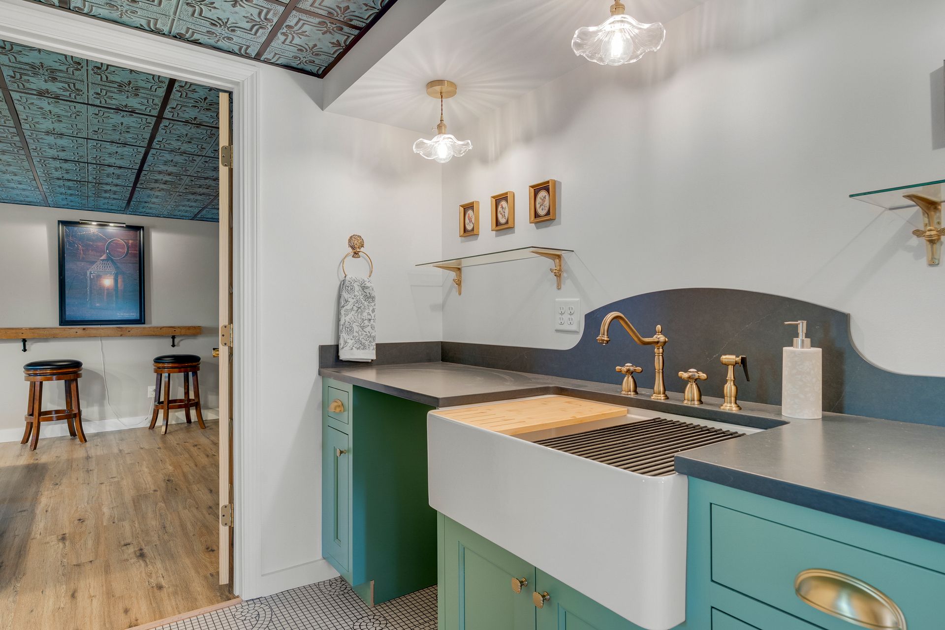 Laundry room with teal cabinets, white sink, gold faucet, and textured ceiling.
