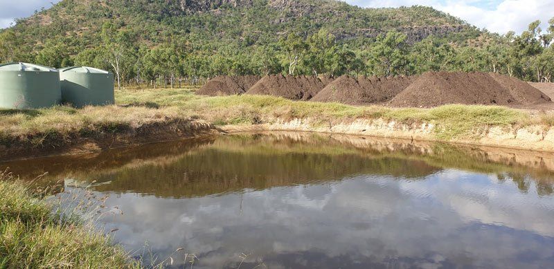 piles of dirt next to small body of water