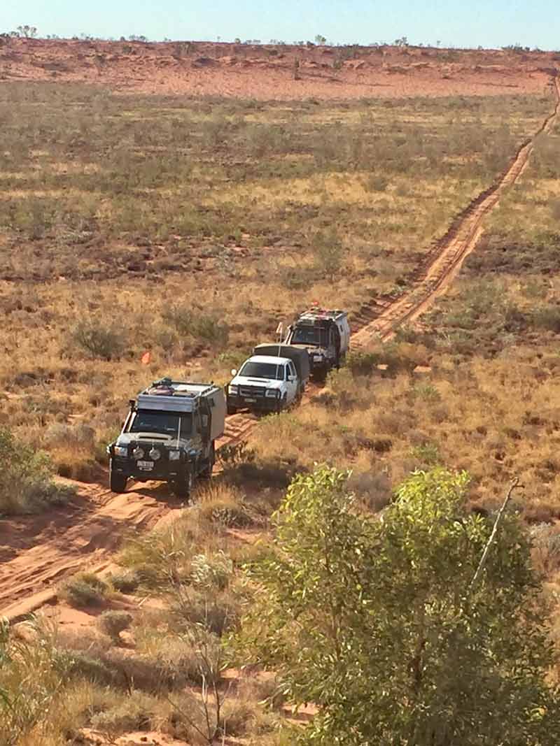 line of cars driving on dirt road