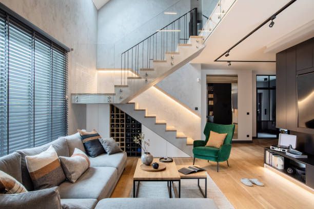 A living room with a couch , chair , table and stairs.