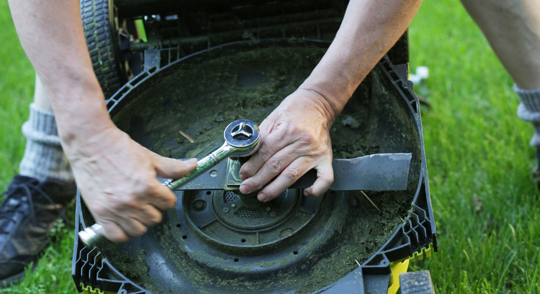 A person is tightening the mulching machine with screw driver