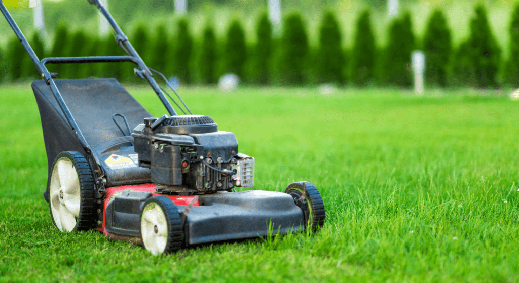 A lawn mower is sitting on top of a lush green lawn.