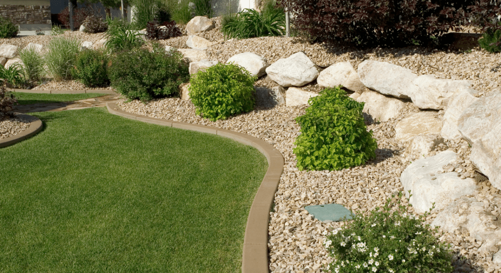 A lush green lawn surrounded by rocks and bushes.