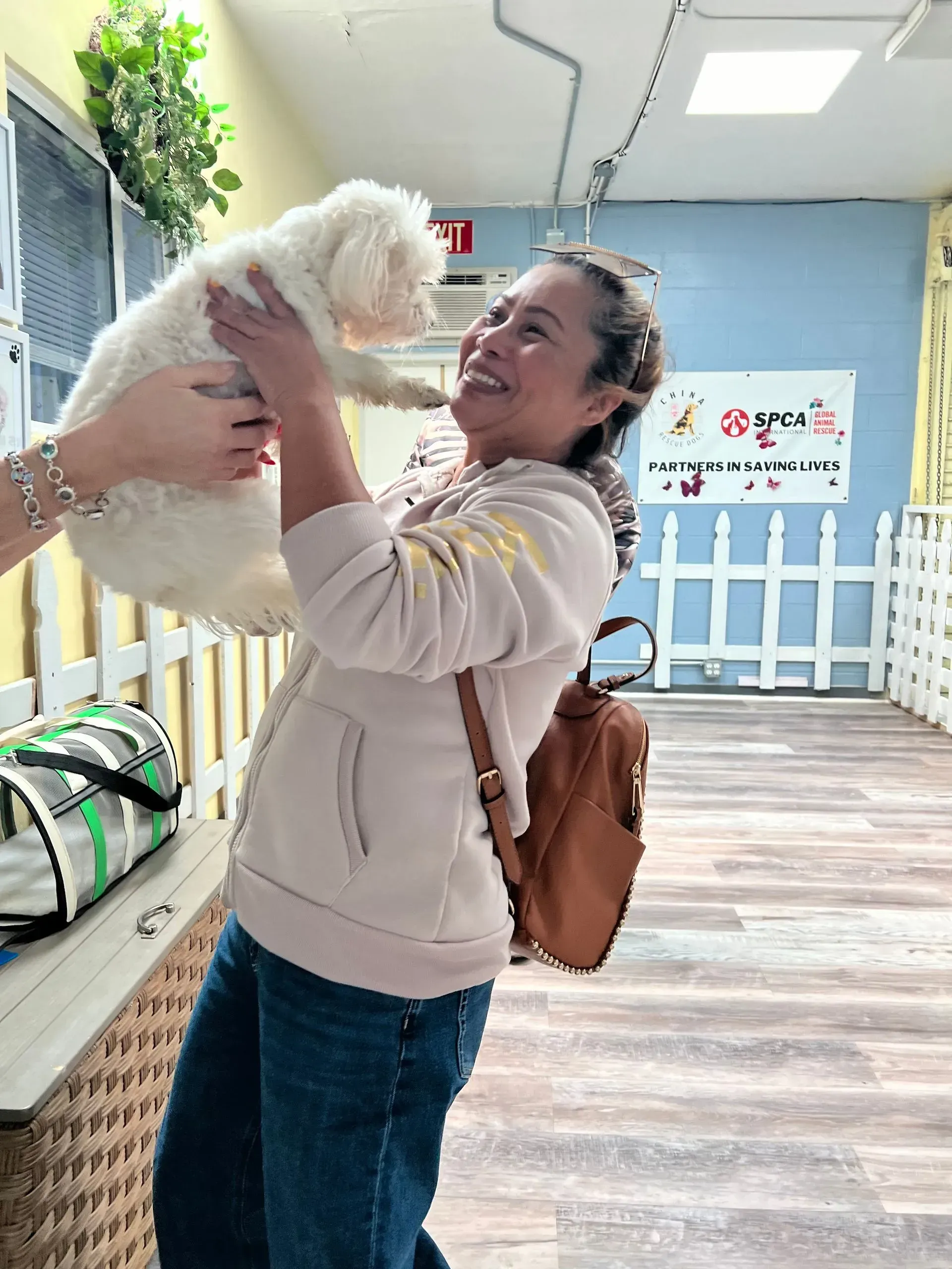 Woman holding a small white dog in a bright indoor play area
