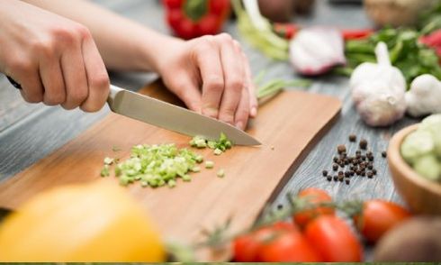 individual chopping vegetables on chopping board