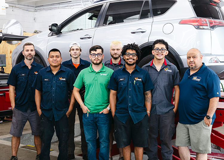Group of mechanics standing in front of a white SUV inside an auto shop in Madison, TN | Pinnacle Automotive