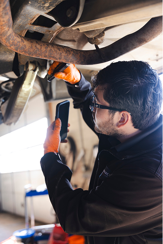 Our expert technician repairing underneath vehicle in our garage | Pinnacle Automotive