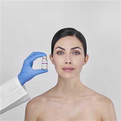 Woman with clear skin facing forward while medical provider holds WiQo bottle for skin rejuvenation treatment