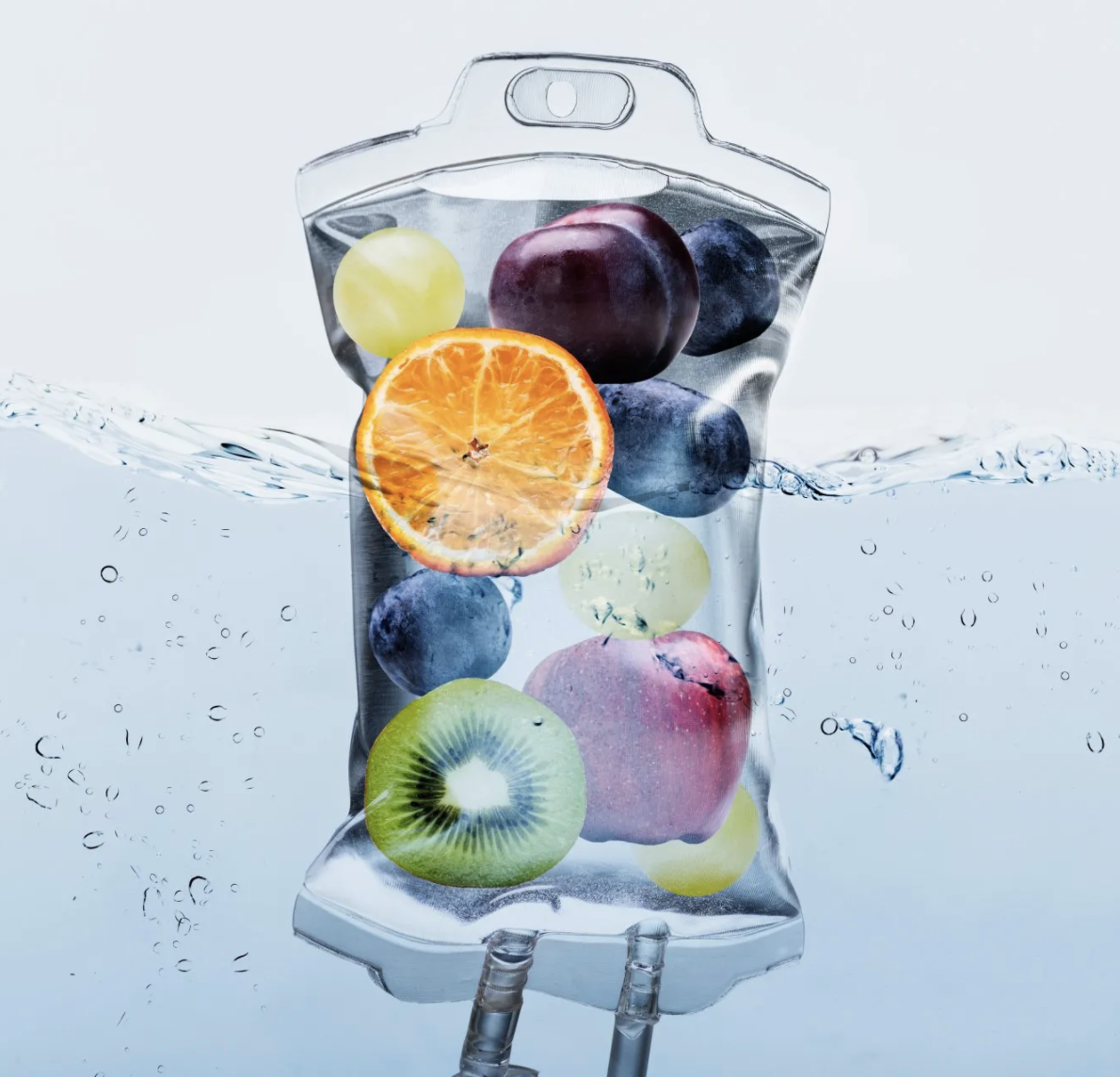 IV hydration bag submerged in water filled with fruits like orange, kiwi, grapes, and apple for vitamin infusion