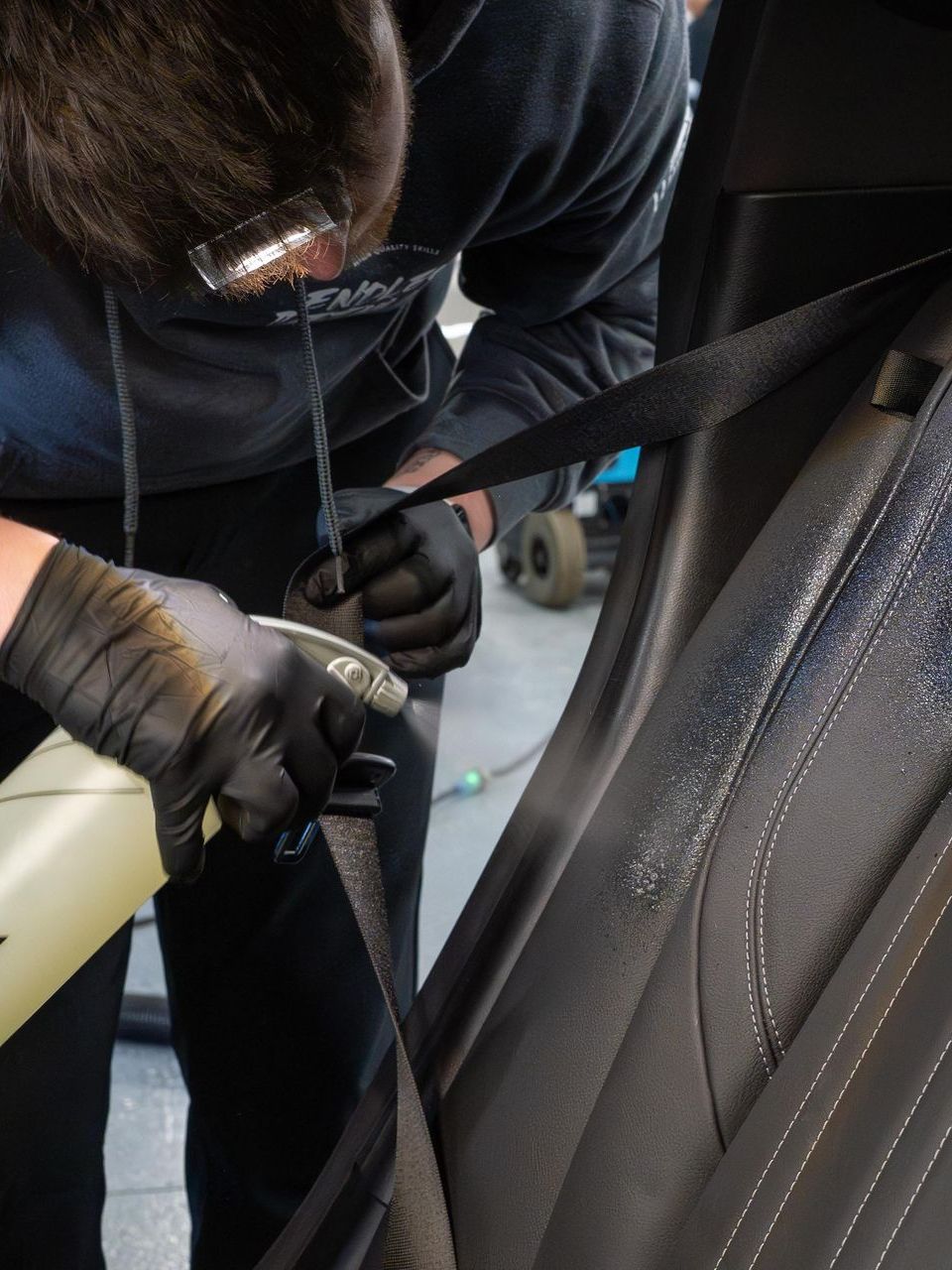 A person wearing black gloves is cleaning a car seat