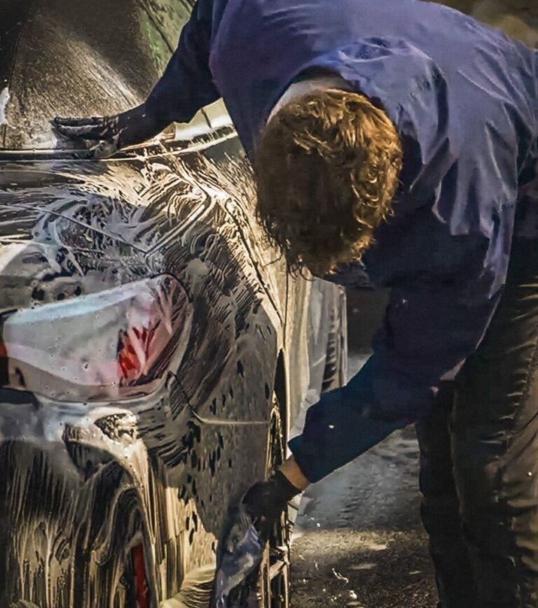 A man is washing a car with soap and water.