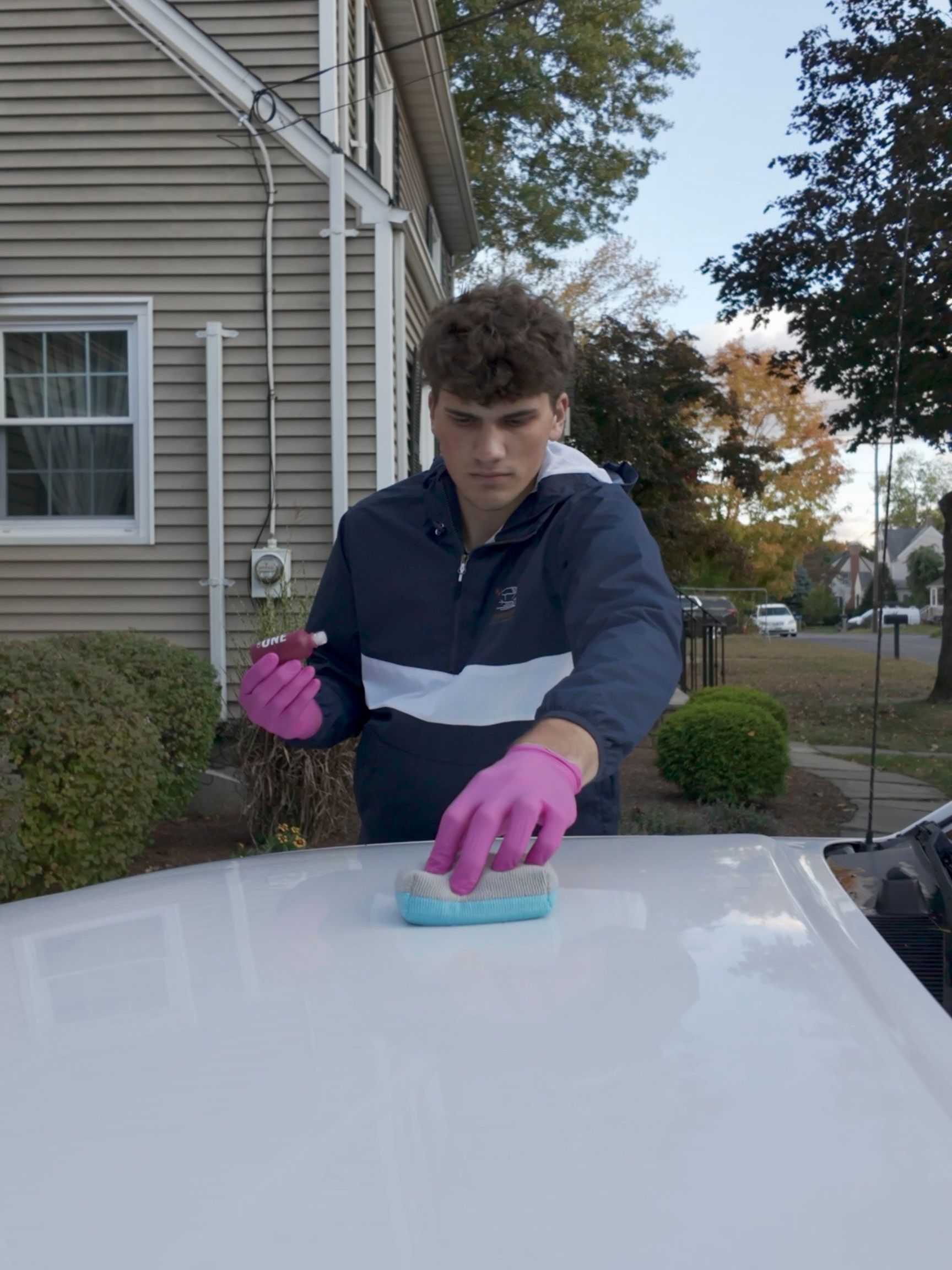 A man is cleaning the wheel of a black car with a sponge.