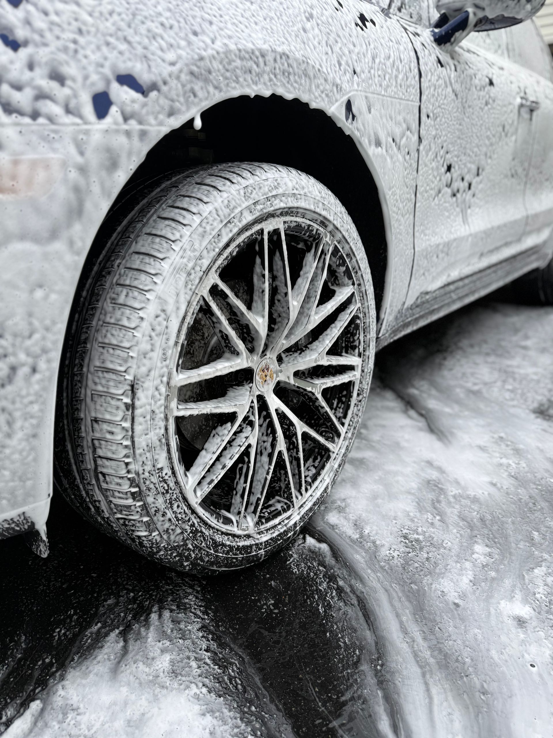 A person is washing a car wheel with foam