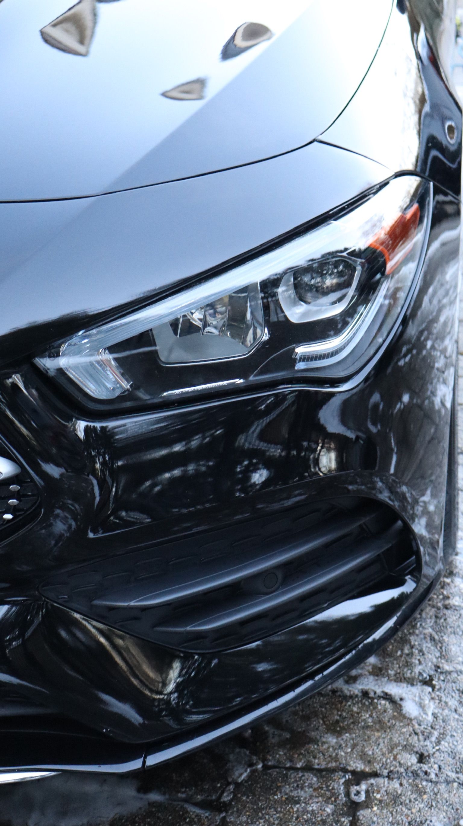 A person wearing black gloves is cleaning the side mirror of a car