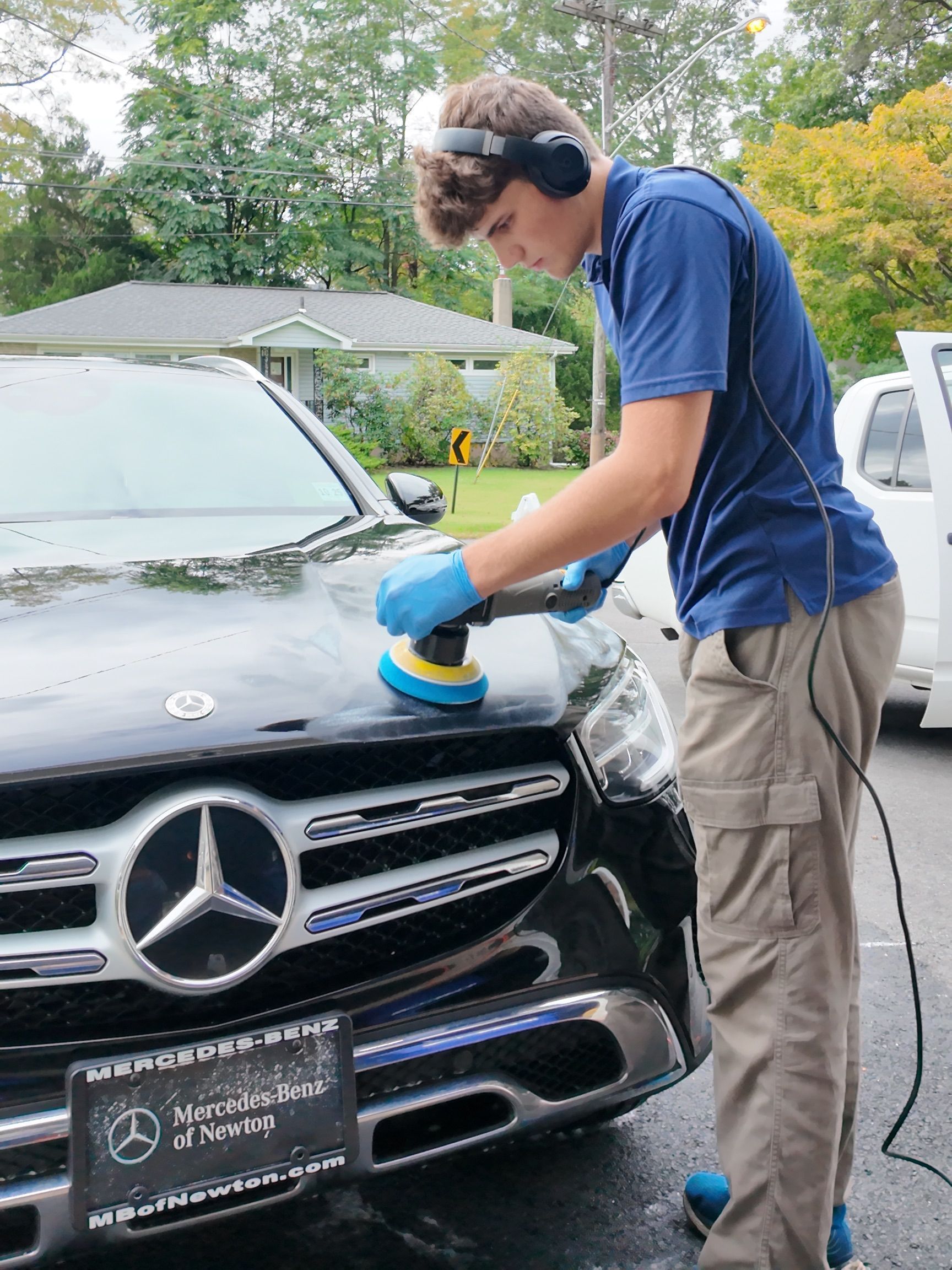 A person wearing black gloves is polishing a black car