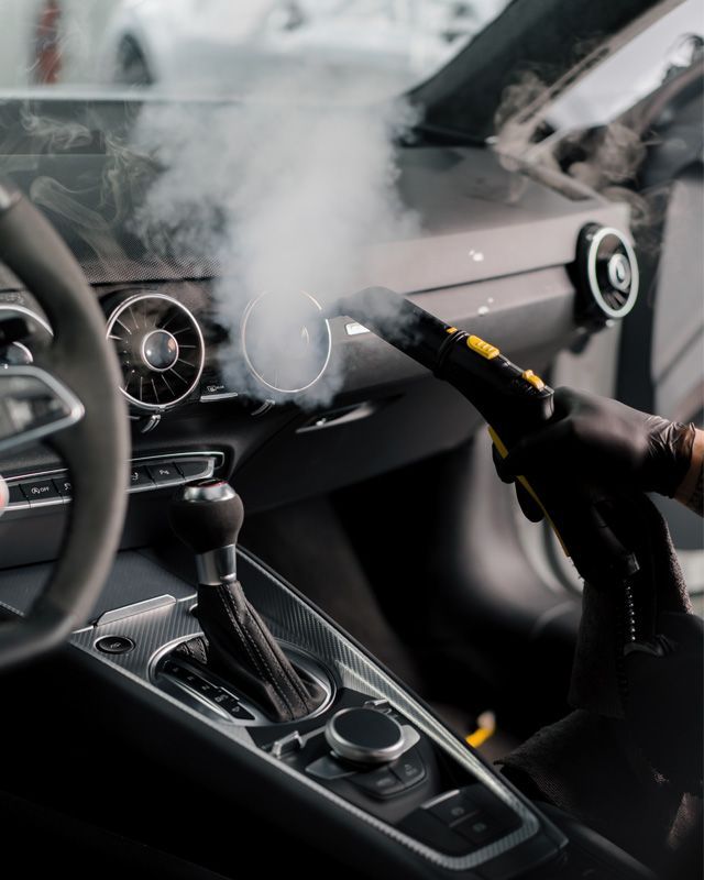 A person is cleaning the interior of a car with a vacuum cleaner.