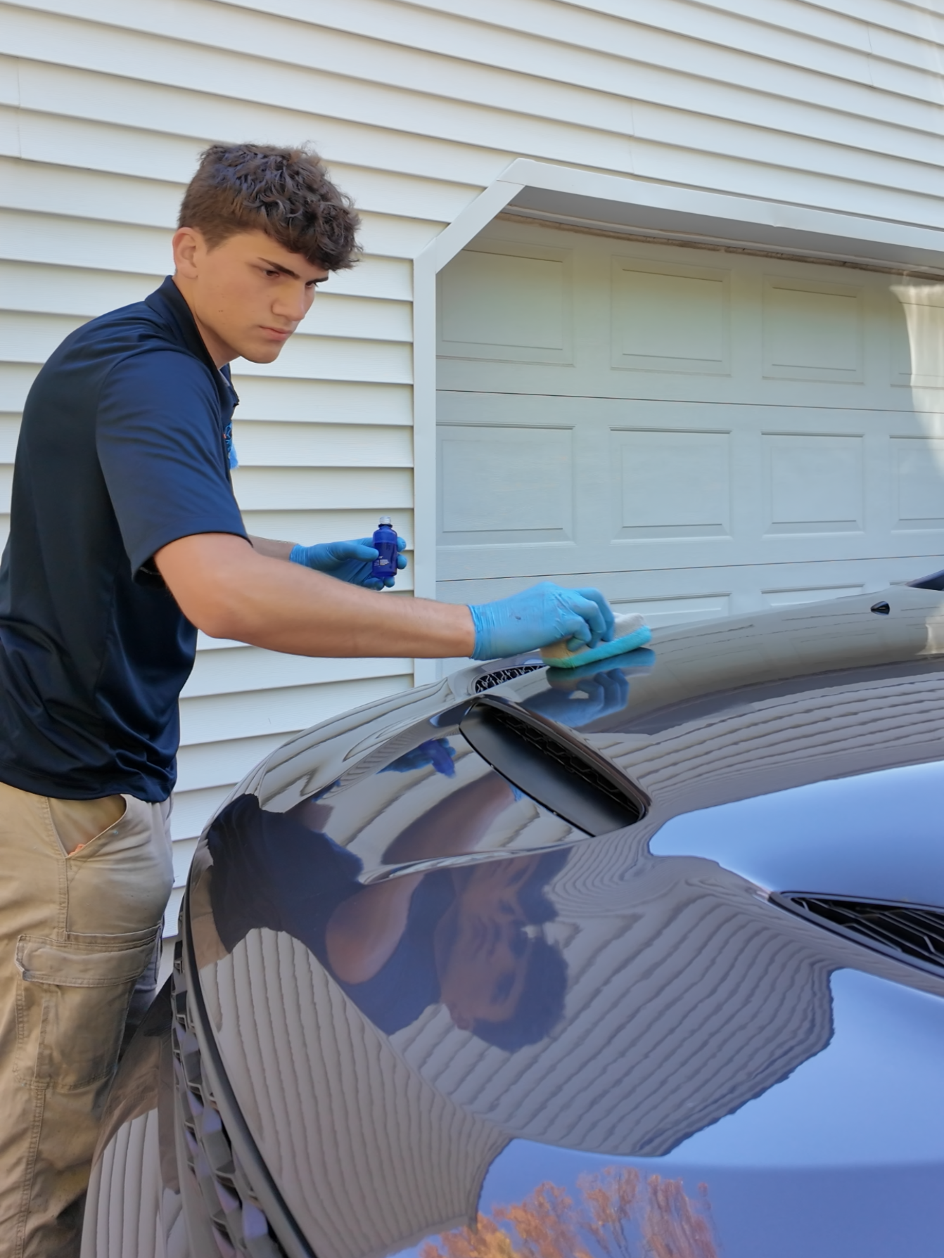 A man is cleaning the windshield of a car.
