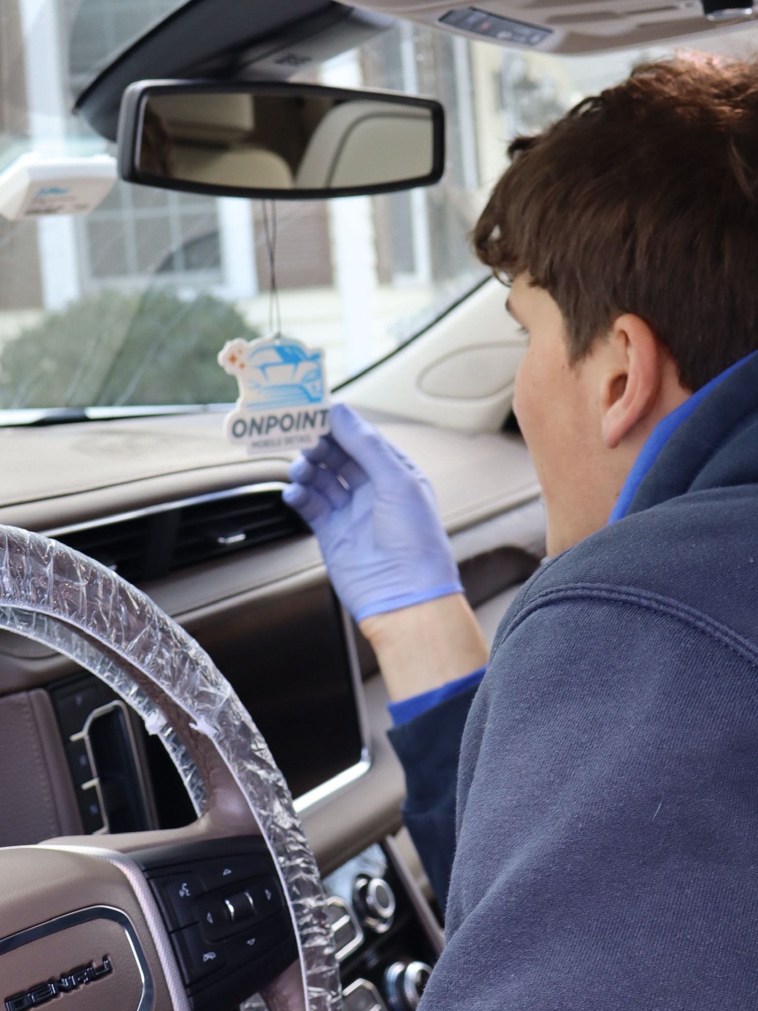 A man is cleaning the wheel of a black car with a sponge.