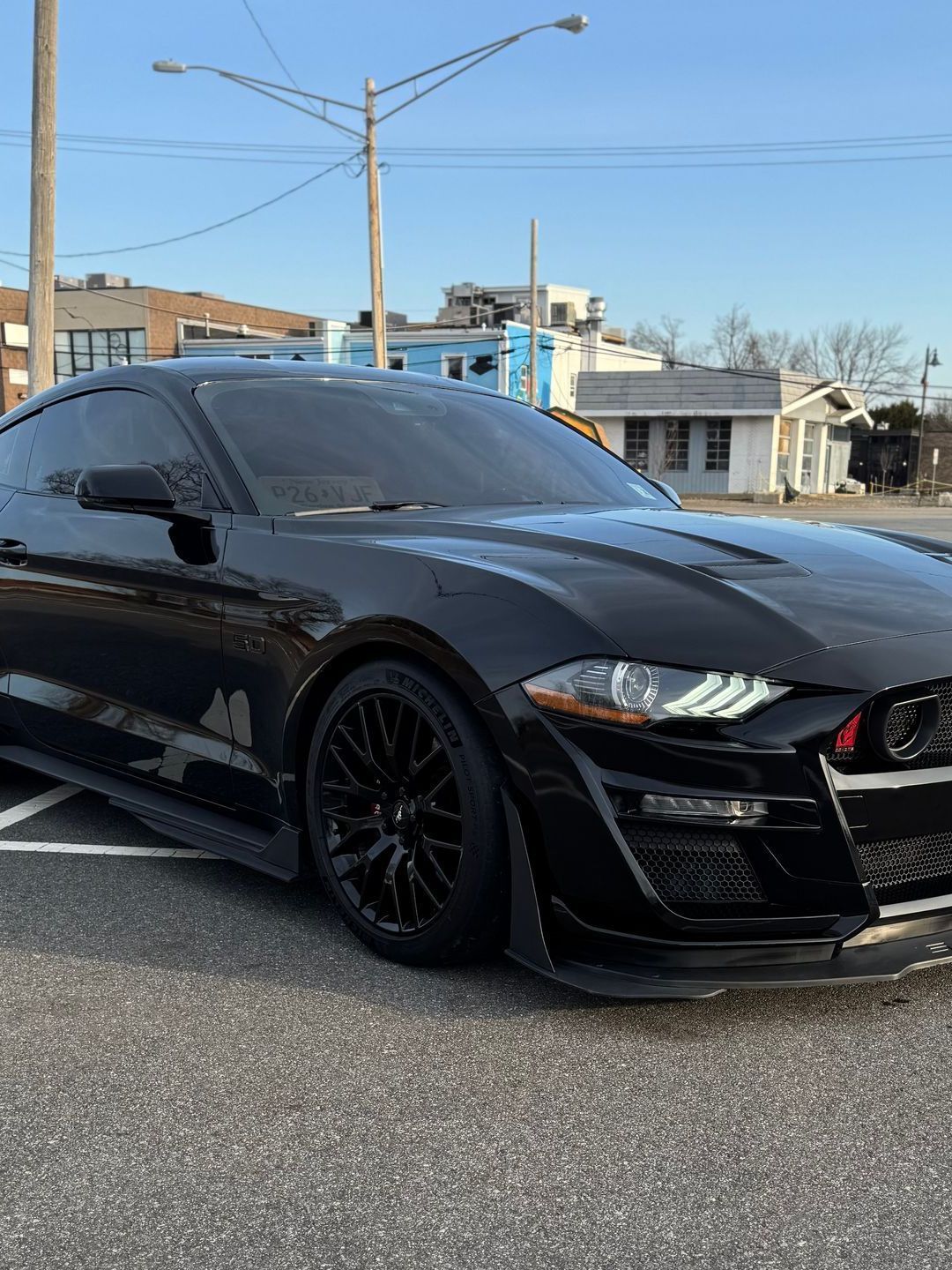 A person wearing black gloves is polishing a black car