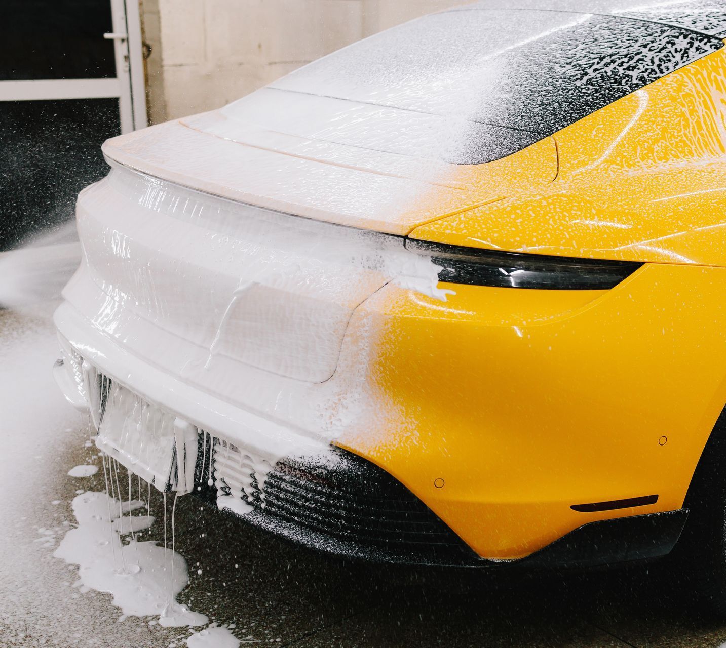 A person is cleaning a blue car with an orange towel
