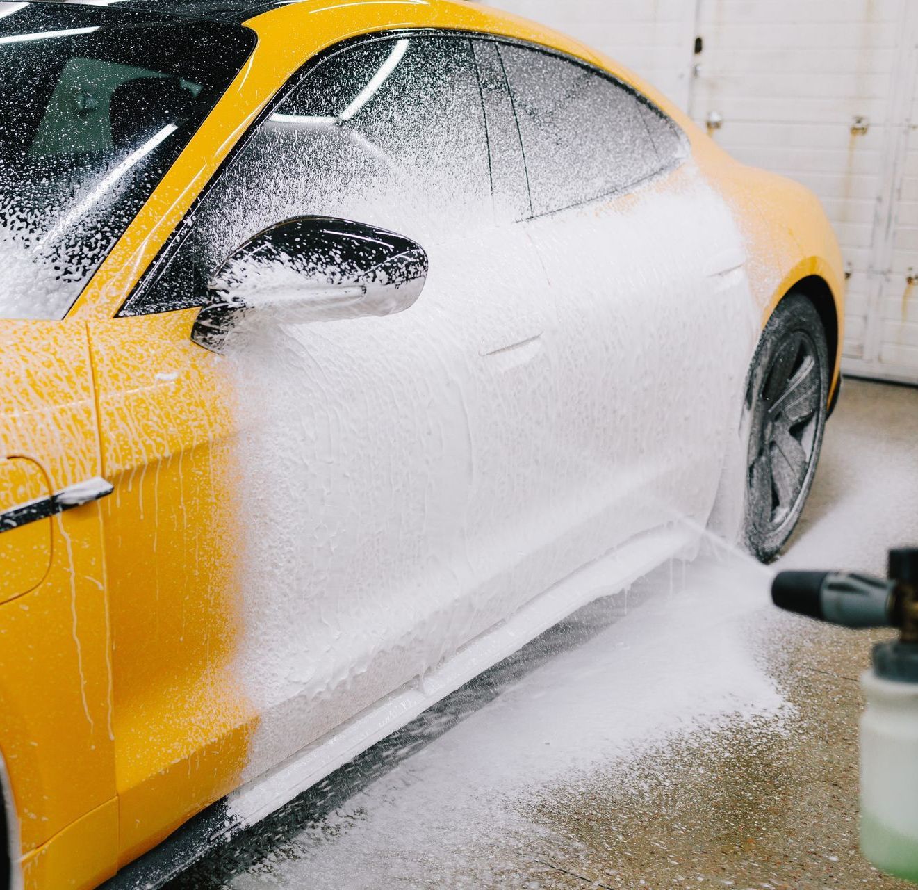 A person is washing a black car with soap and water.