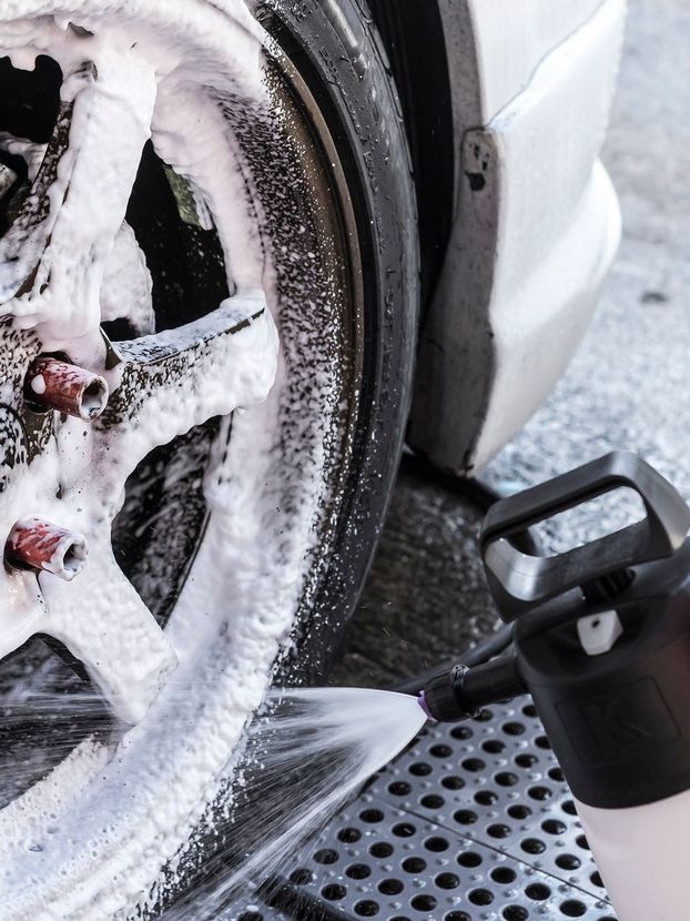 A person is washing a car wheel with foam