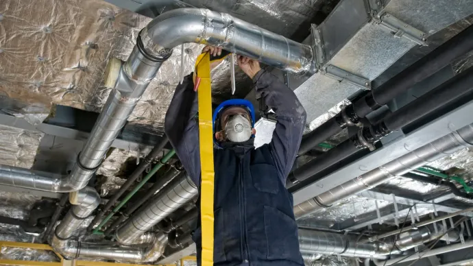 A man is measuring a pipe with a tape measure.