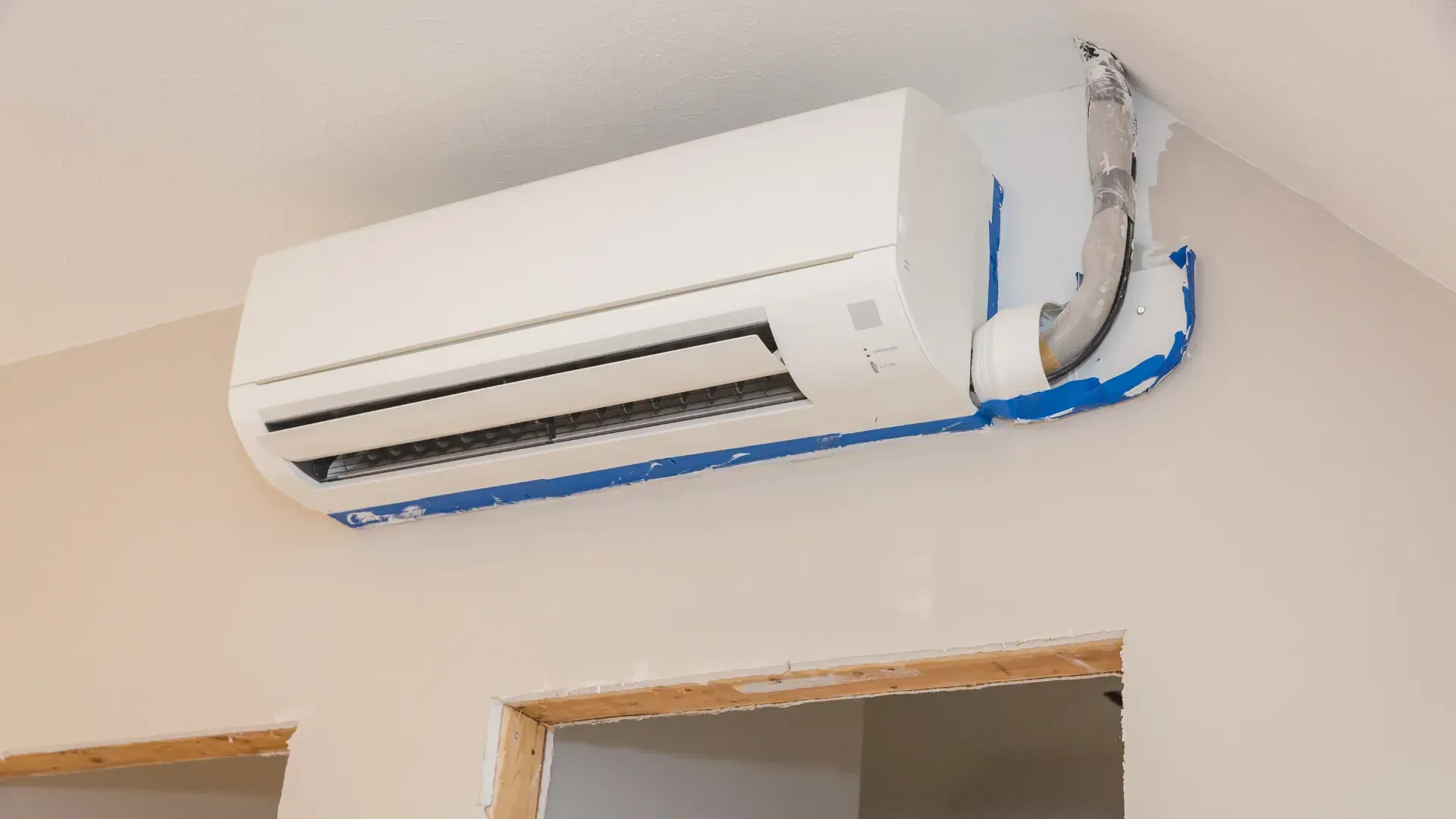A wall mounted air conditioner is being installed in a room.