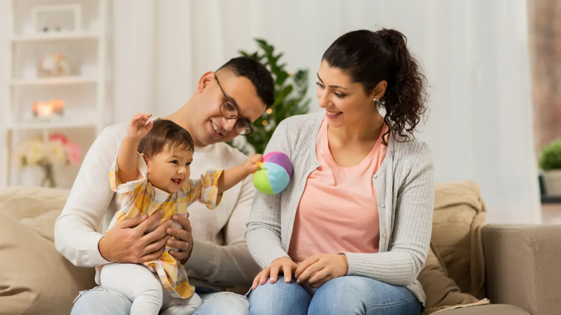 A man and a woman are sitting on a couch with a baby.